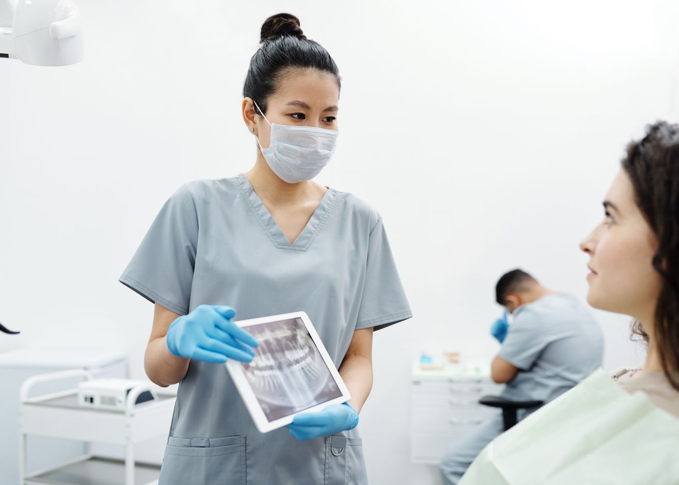 A dentist showing a patient her dental X-ray on a tablet